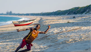 A man on a beach uses a rope to pull something out of the water.