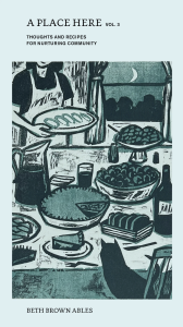 A Place Here Volume 3 by Beth Brown Ables, featuring an illustration of a baker putting rolls and pie down on a table with a cat watching on a blue background.