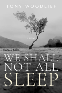Cover of We Shall Not All Sleep by Tony Woodlief featuring white text over a black and white photograph of a tree standing in the middle of a body of water with mountains in the distance. 